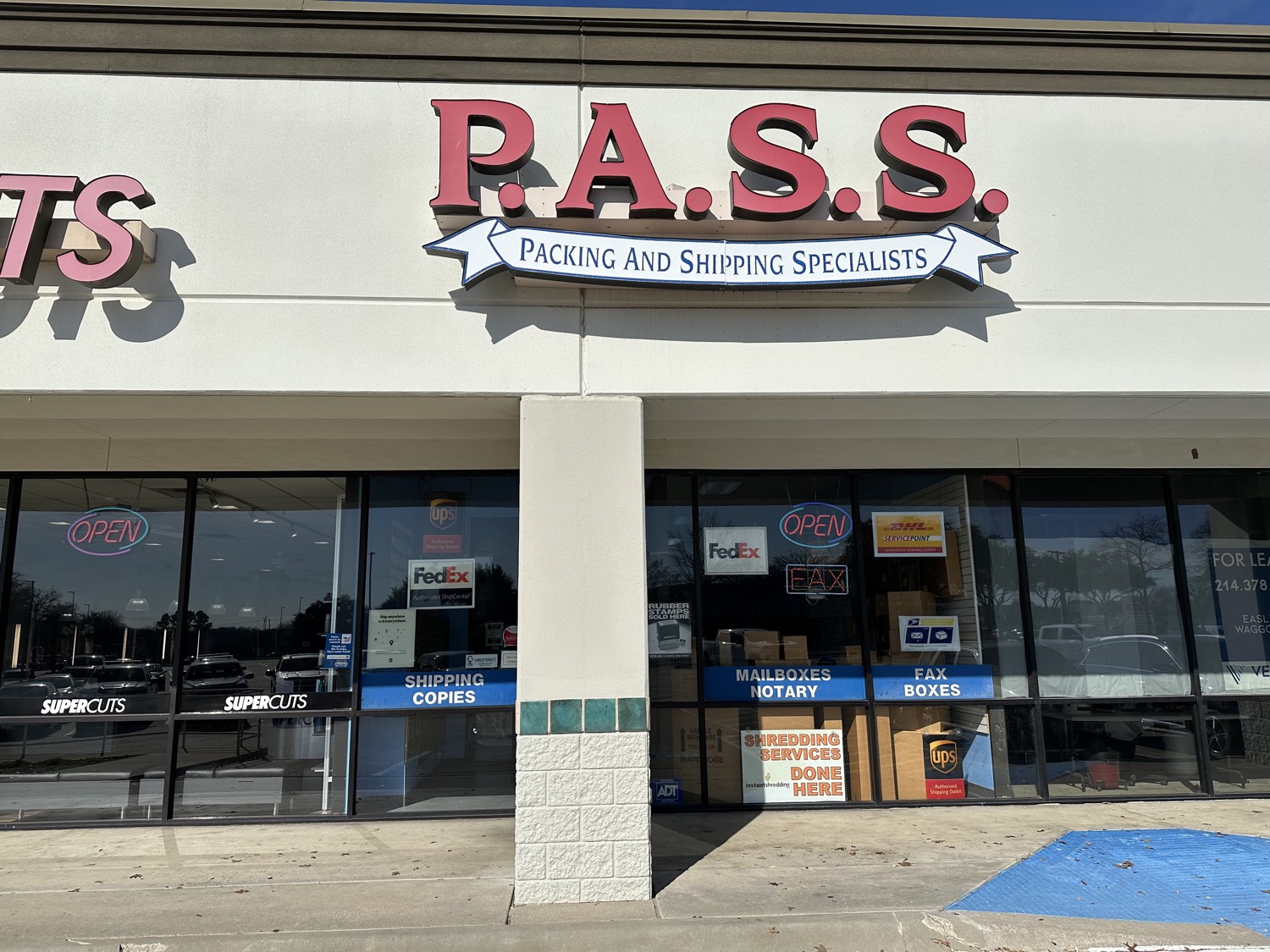 PASS Postal Center storefront: red P.A.S.S. letters and a Packing And Shipping Specialists ribbon, next to Supercuts at 5904 S. Cooper Street